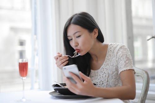 Free Asian young female eating noodles at cafe Stock Photo