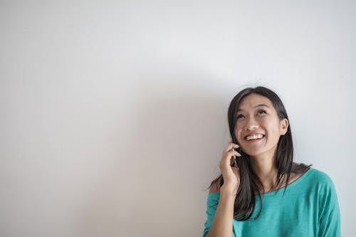 Porträtfoto Der Lächelnden Frau In Einem Blaugrünen Oberteil, Das Am Telefon Spricht