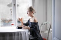 一位时尚的女士在明亮的窗前品尝着红酒意大利面