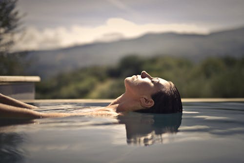 Free Selective Focus side View Photo of a Woman with Her Eyes Closed Resting Her Head in Water Stock Photo