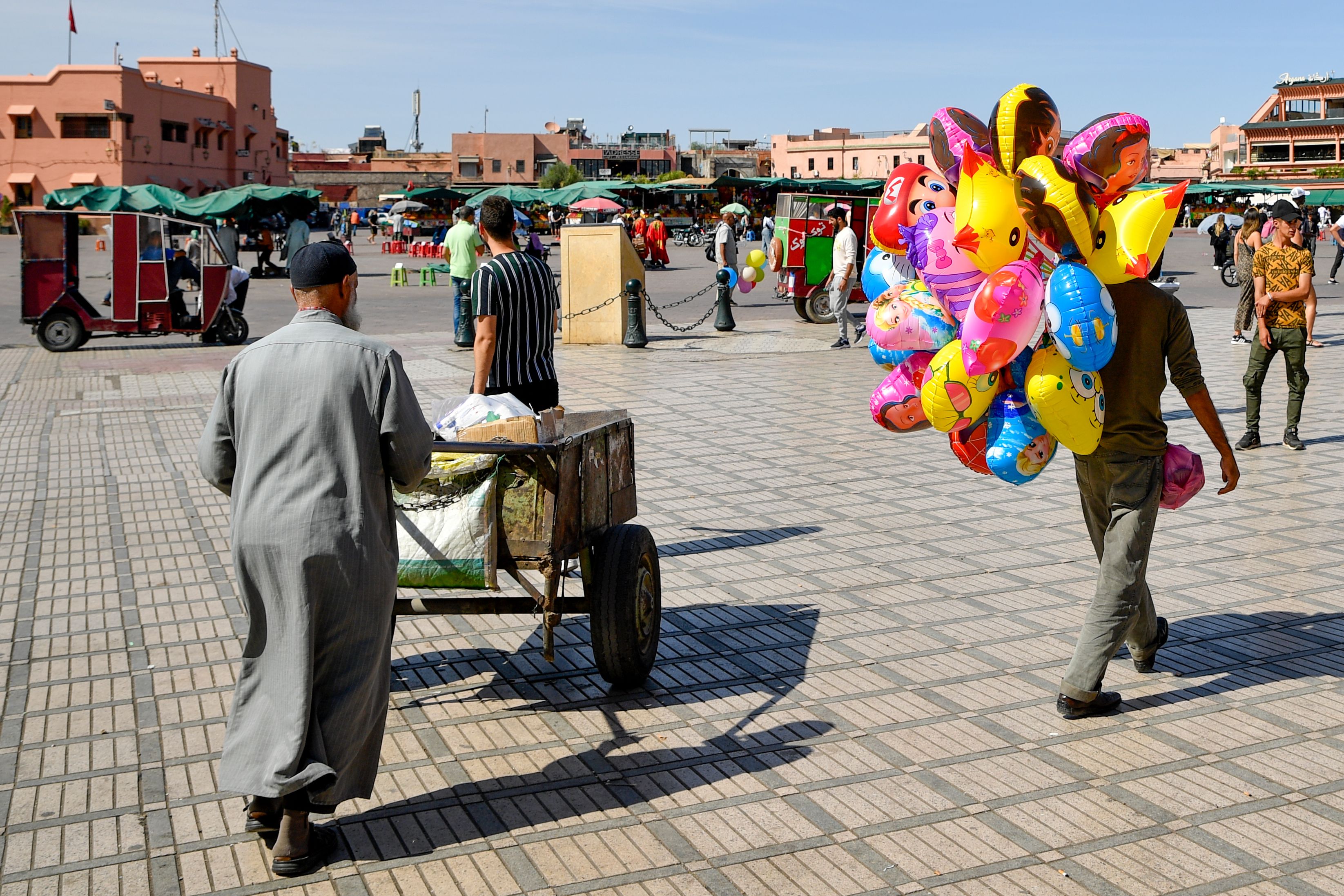 Colorful scene of people and vendors in bustling Jemaa el-Fnaa square, Marrakesh, Morocco, capturing vibrant local culture.