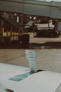 Close-up of airplane wing with visible 'push' and 'pull' tab, airport ground services in background.