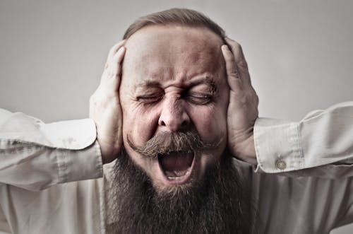 Free Close-up Photo of Screaming Man With a Full Beard Covering His Ears and Closing His Eyes Stock Photo