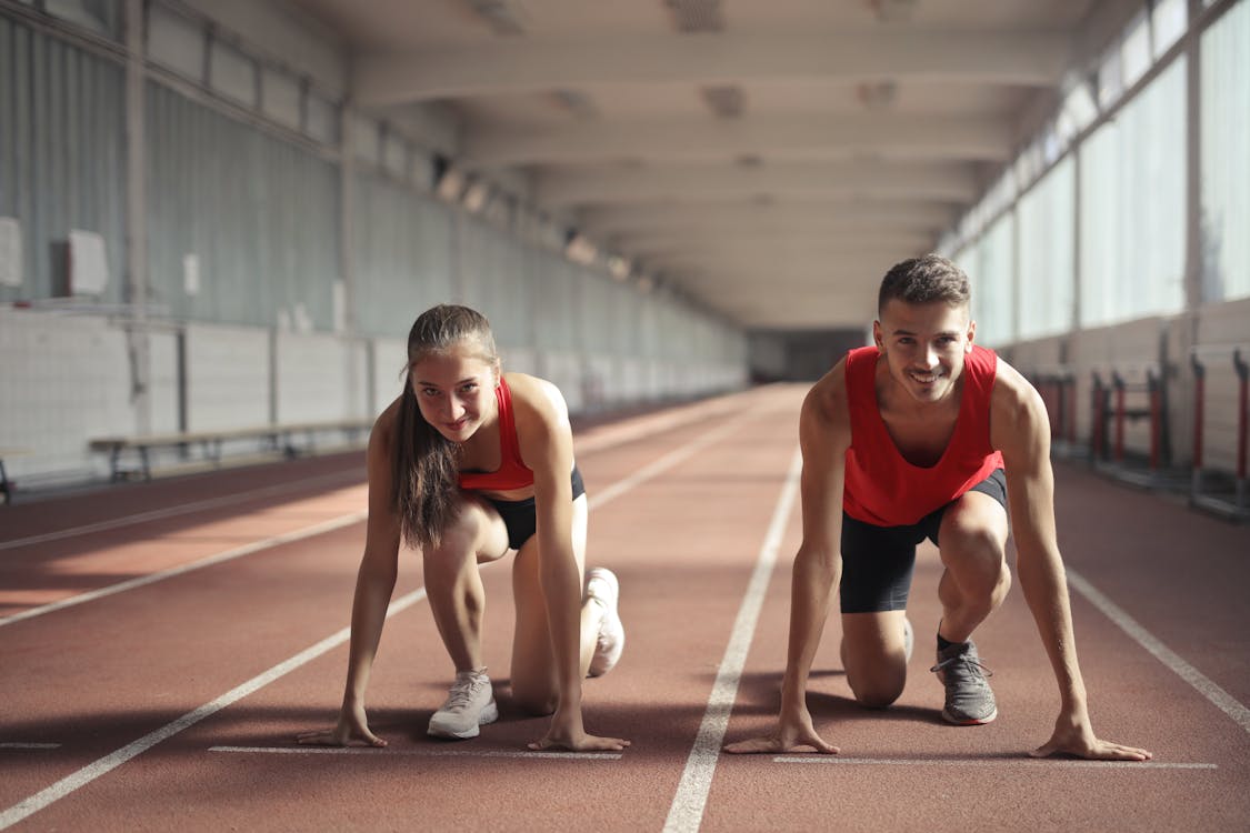 Homens E Mulheres De Camiseta Vermelha Estão Prontos Para Correr No Campo De Atletismo