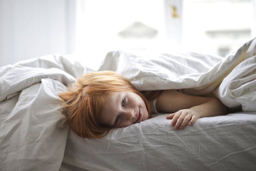 免费 孩子躺在床上覆盖她的身体在毯子上 素材图片