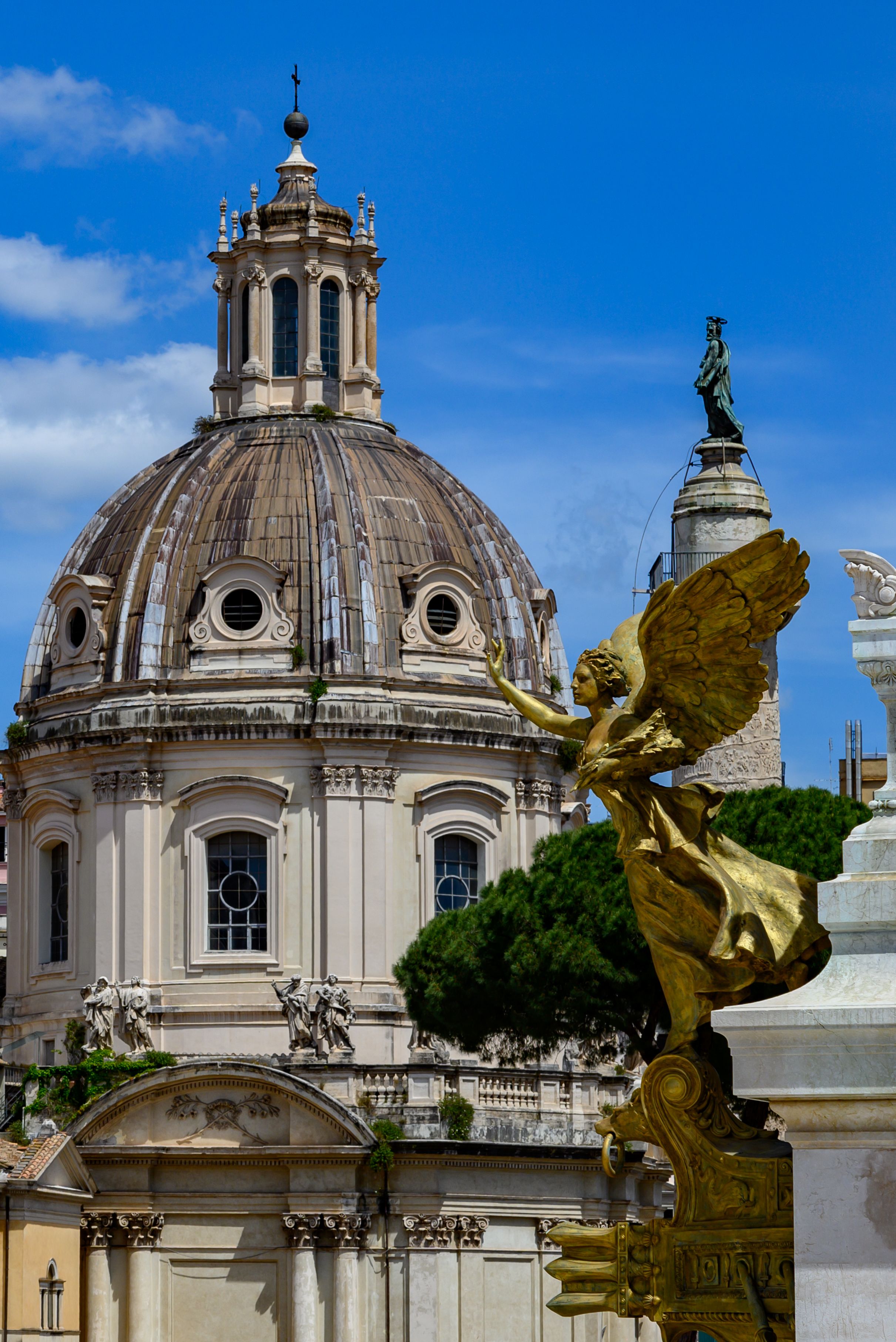 Gold angel sculpture with historic domed building in Rome's vibrant cityscape.