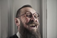 一个戴着眼镜、留着胡须的男人在室内快乐大笑的特写镜头