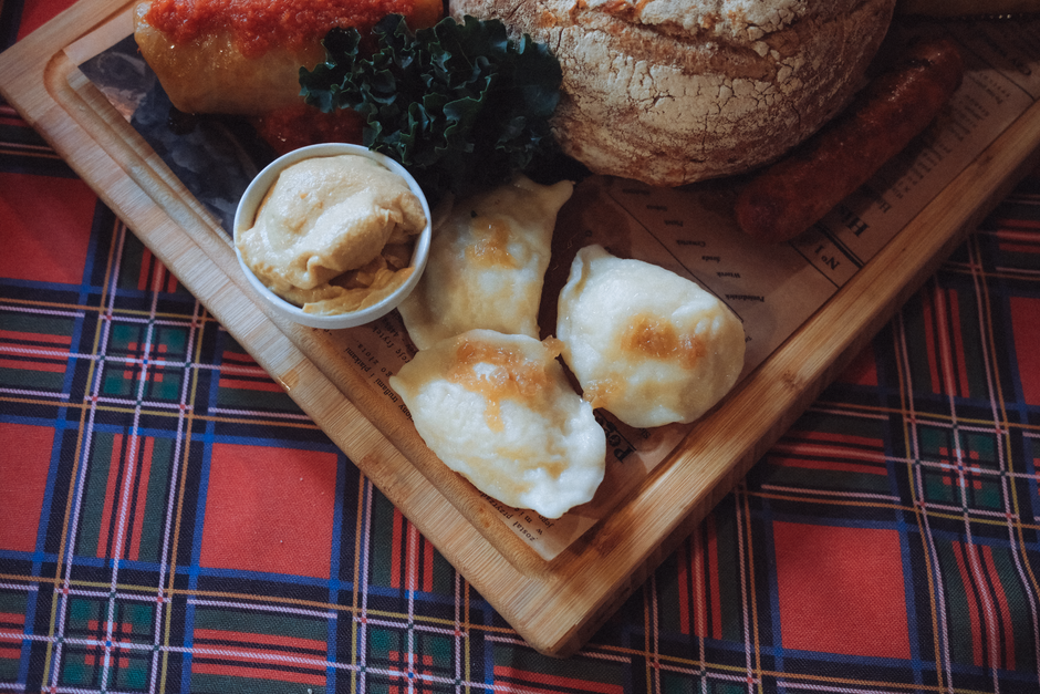 A plate of hearty Cepelinai (potato dumplings) with sour cream and bacon bits in a Lithuanian restaurant.