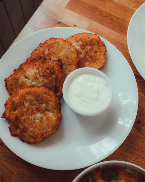 Free Crispy Polish potato pancakes served with creamy sour cream on a white plate. Stock Photo