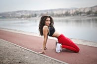 一名穿着运动服的女子在河边小路上伸展，宣传积极的生活方式