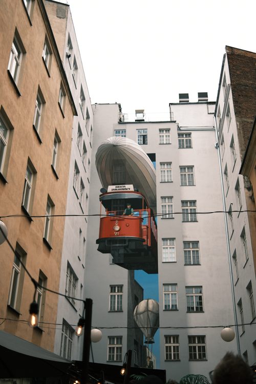 Free An artistic mural featuring a tram and balloon decorates a Warsaw building facade in vibrant urban style. Stock Photo