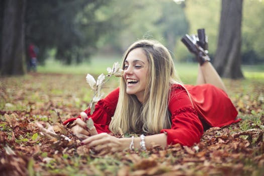 一位穿着红色连衣裙的快乐女人正在公园里欣赏秋叶