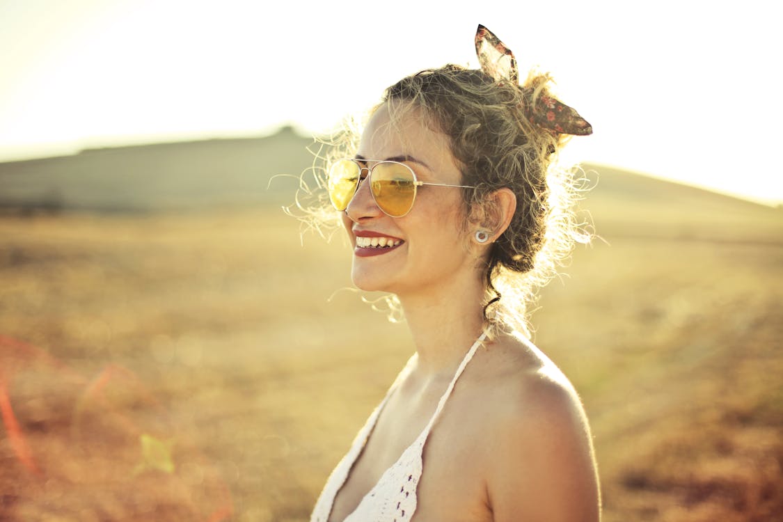 Selective Focus Side view Photo of Smiling Woman in White Top Wearing Aviator Sunglasses