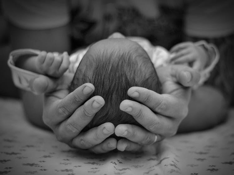 Hands Holding Head Of Newborn