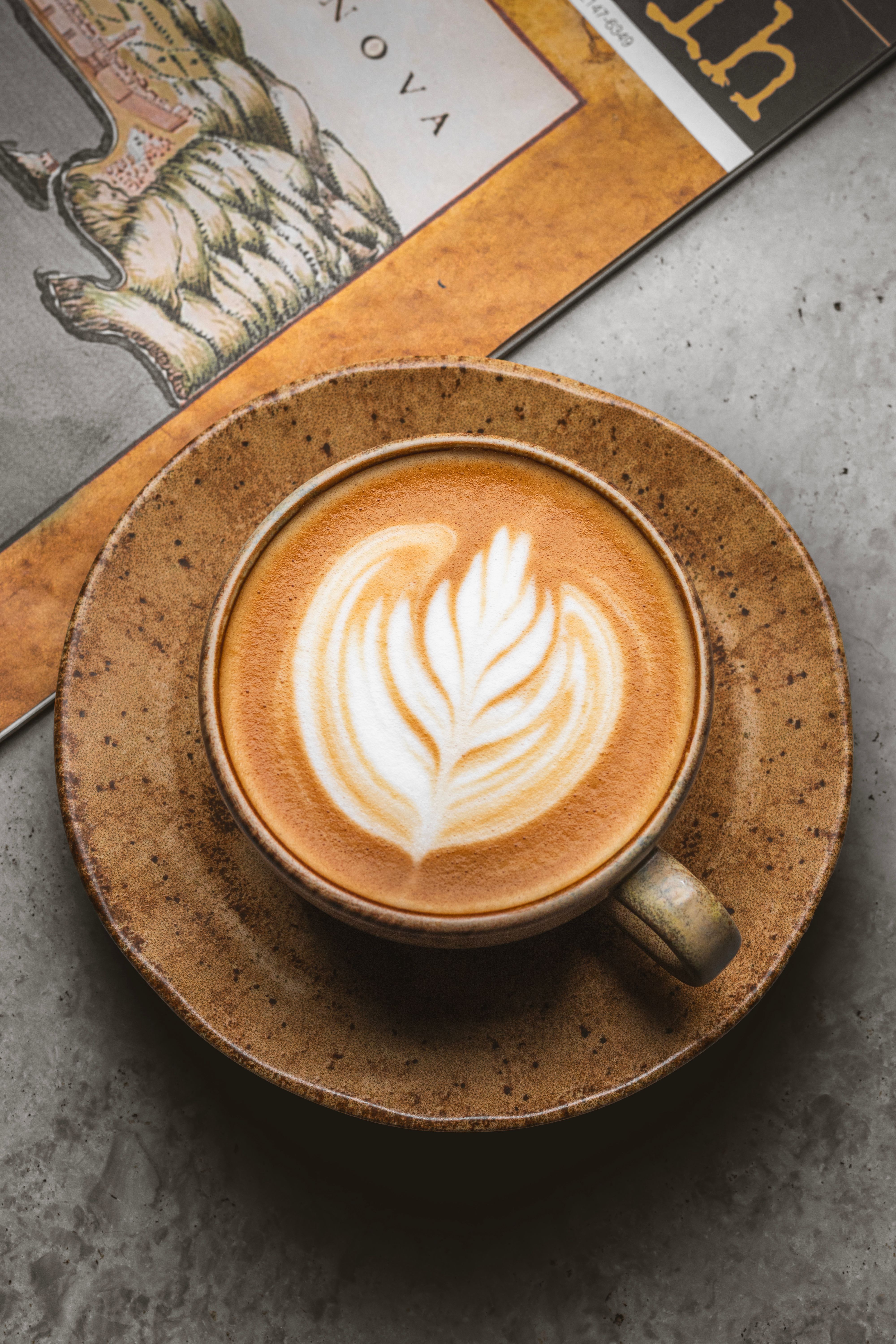 Cappuccino et son latte art dans une tasse en grès posée sur sa soucoupe