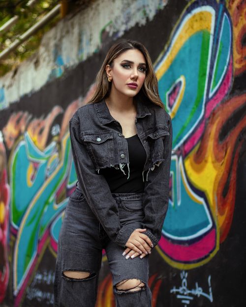Free Stylish woman in a denim outfit poses confidently against a vibrant graffiti wall. Stock Photo