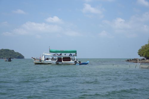Free A tranquil scene with a boat on clear blue waters, surrounded by lush greenery. Stock Photo