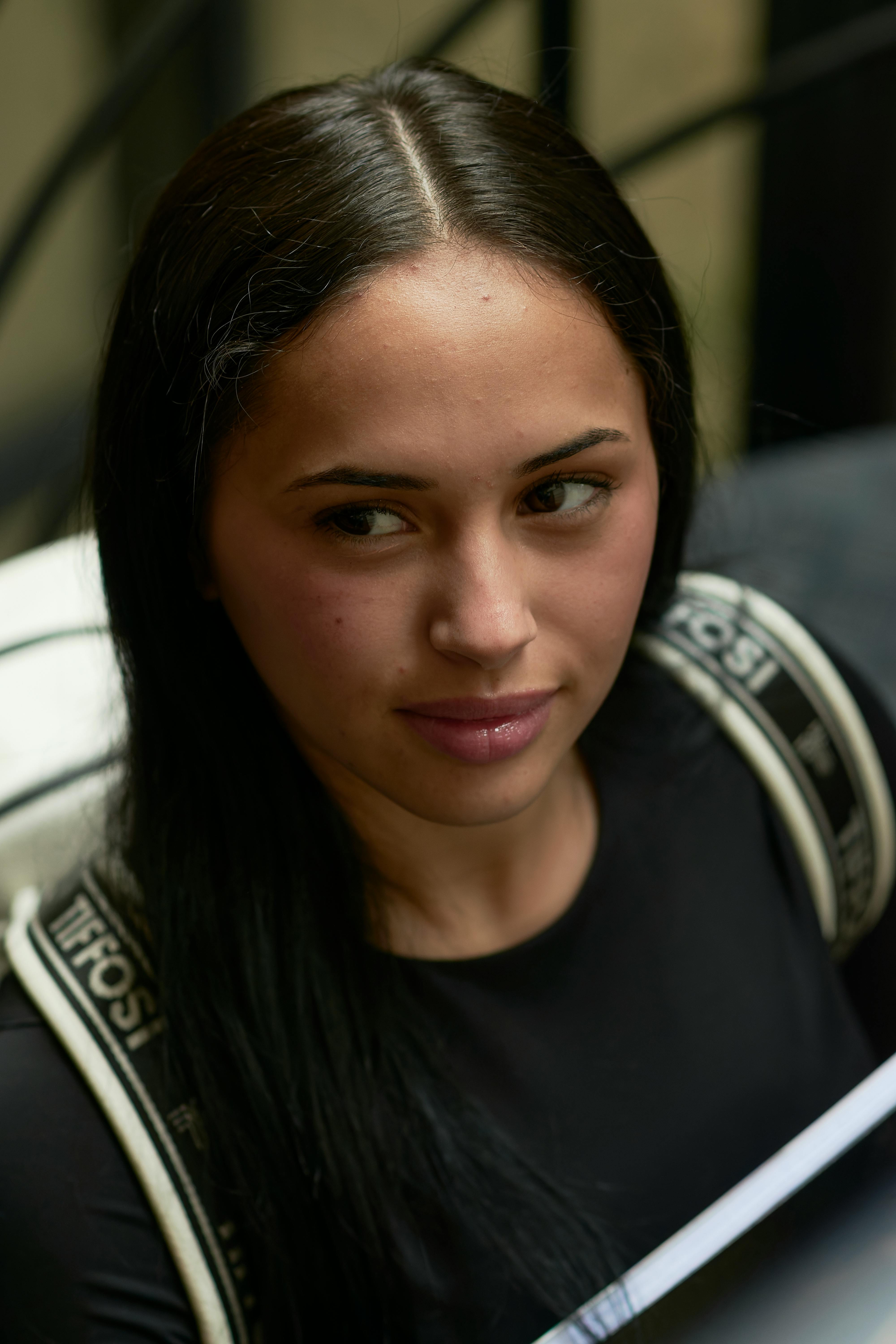 Close-up portrait of a young woman outdoors with a backpack.