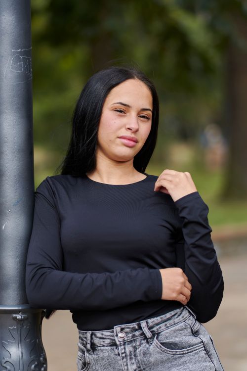 Free A confident young woman poses by a lamppost in a park setting, Uruguay. Stock Photo