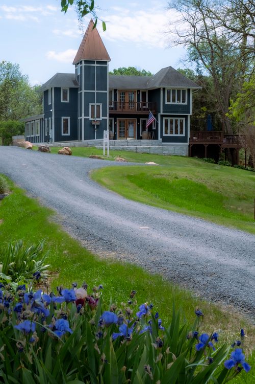 Free Victorian house with a winding gravel driveway and blooming garden in spring. Stock Photo