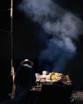 A market vendor surrounded by produce with dramatic smoke in an atmospheric setting.
