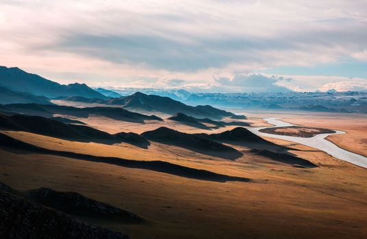 Explore a vast skyline of mountains and rolling landscapes with a winding river cutting through the scenery.
