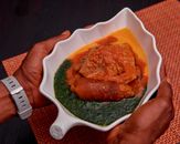 A vibrant African dish featuring meat stew and greens in a unique leaf-shaped bowl.