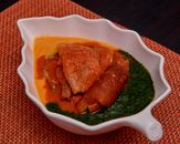 Leaf-shaped bowl with traditional African soup featuring meat and vegetables.