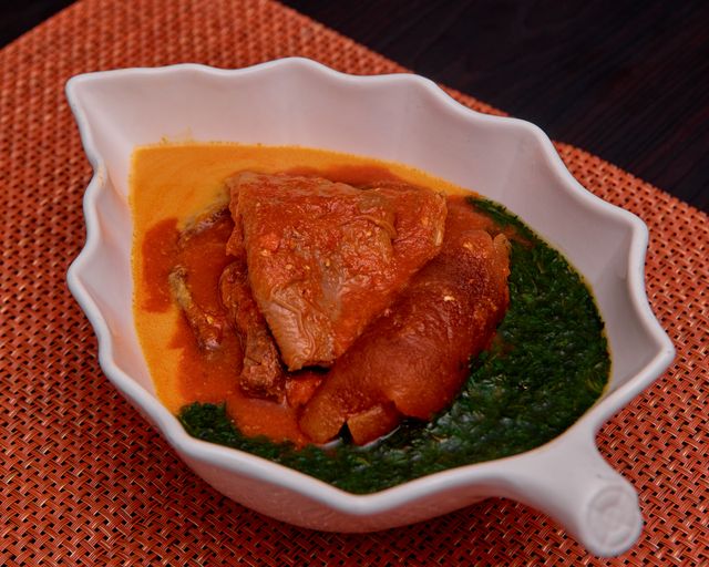 Leaf-shaped bowl with traditional African soup featuring meat and vegetables.
