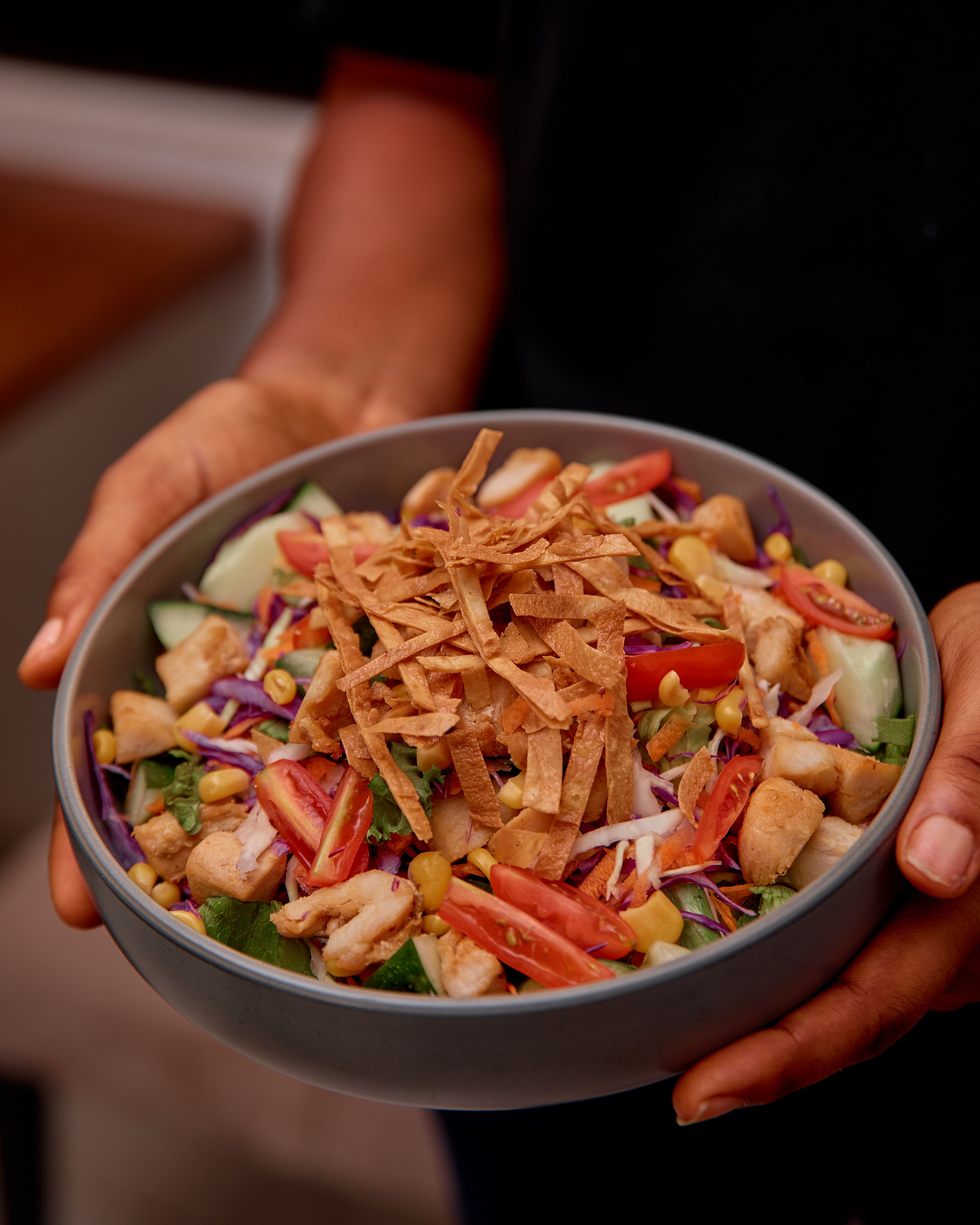 Delicious chicken salad with crispy tortilla strips and fresh veggies in a bowl.