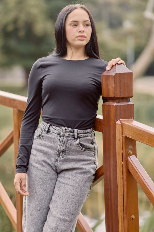 Free A young woman in casual attire leaning on a wooden bridge railing outdoors during daytime. Stock Photo
