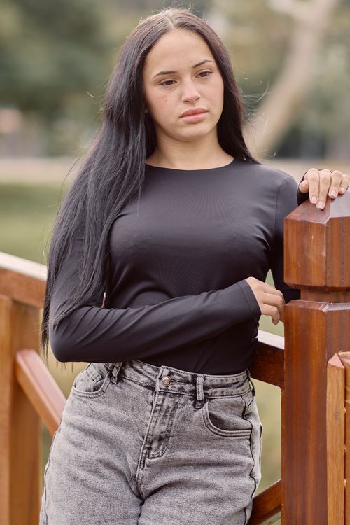 Free Casual portrait of a young woman leaning by a wooden railing outdoors in Uruguay. Stock Photo