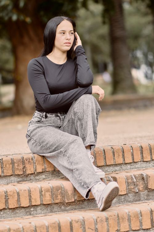 Free Portrait of a young woman in casual clothing sitting on brick steps outdoors in Uruguay. Stock Photo
