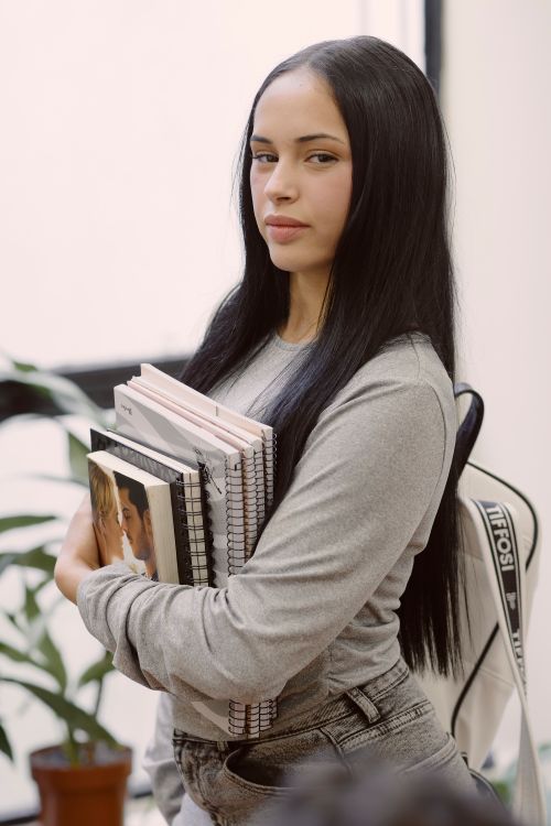 Free Young woman casually holding notebooks in a classroom setting, Uruguay. Stock Photo