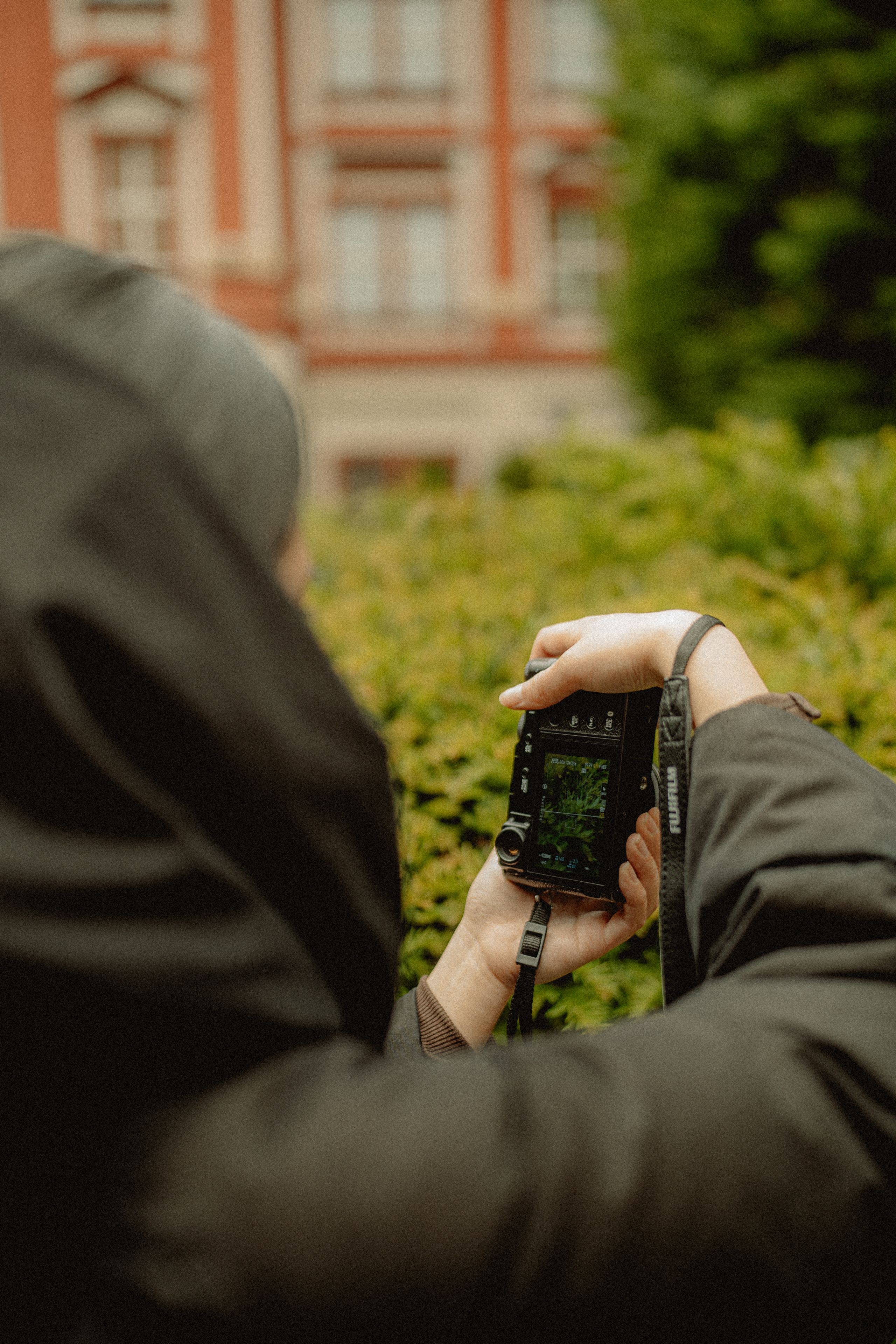 A person taking a photo with a digital camera in a cityscape setting.