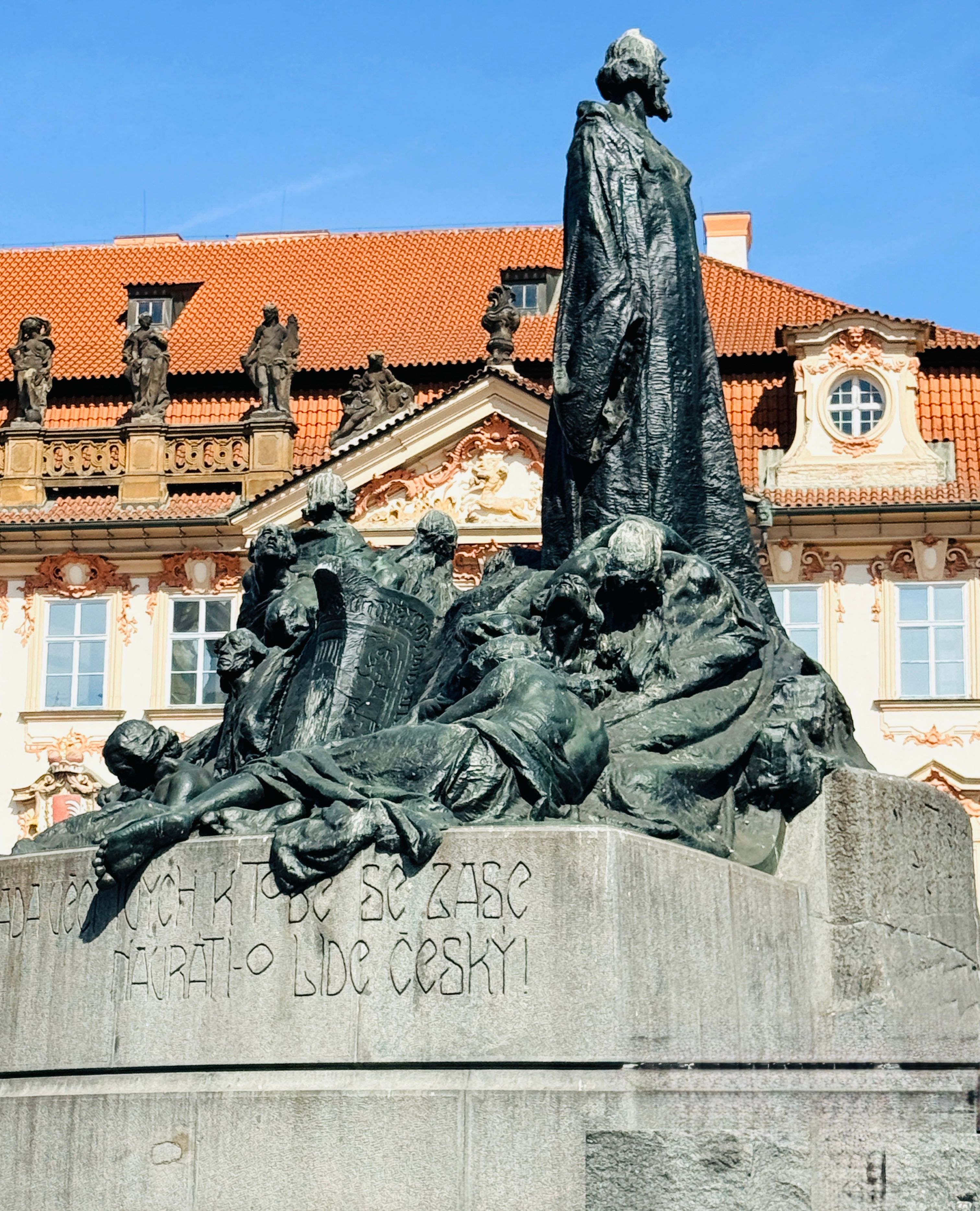 Jan Hus Monument in Prague's Old Town, set against a baroque building backdrop.