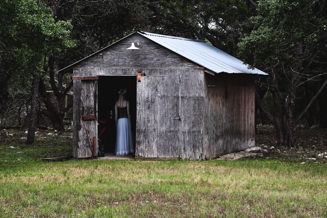 a solitary wooden cabin in the forest with a mysterious figure by the