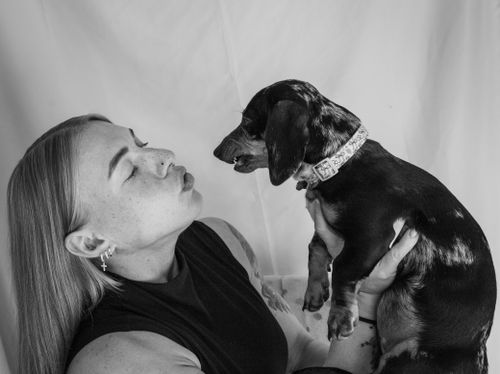 Free Portrait of woman affectionately interacting with her Dachshund in black and white. Stock Photo