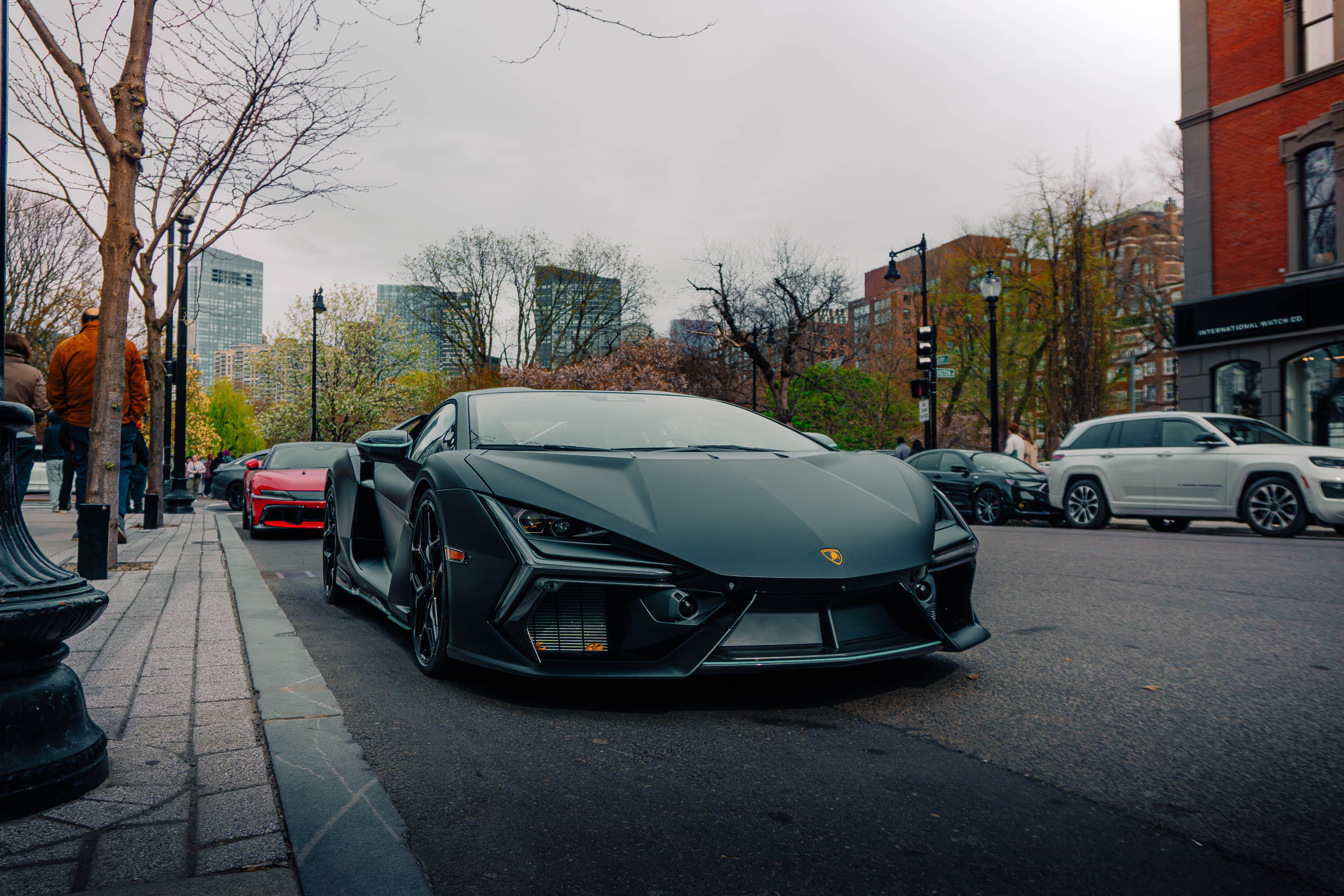Black sports car on a city street, showcasing modern design and luxury.
