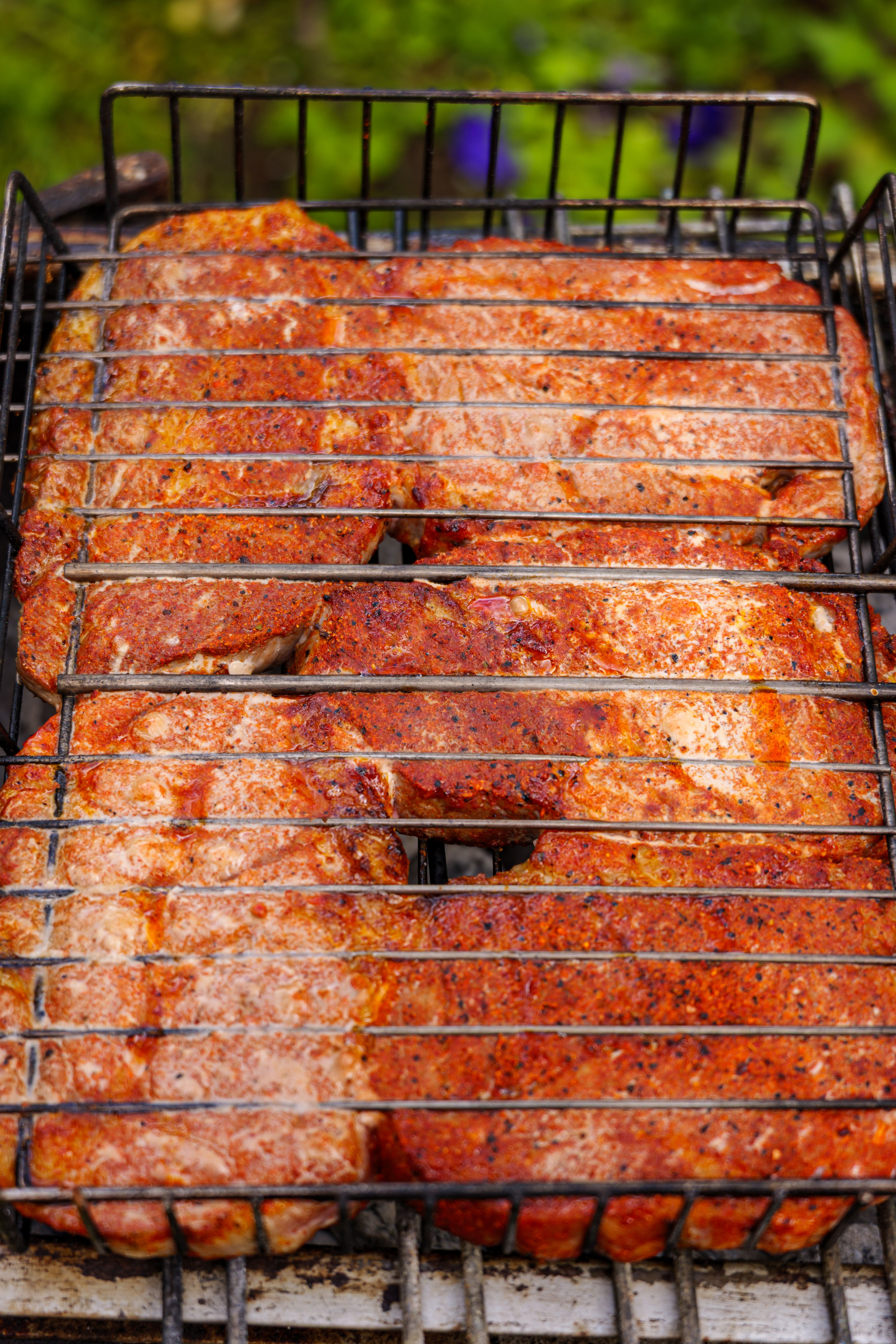 Flavorful grilled pork chops sizzling on a charcoal barbecue outdoors, perfect for a summer BBQ.