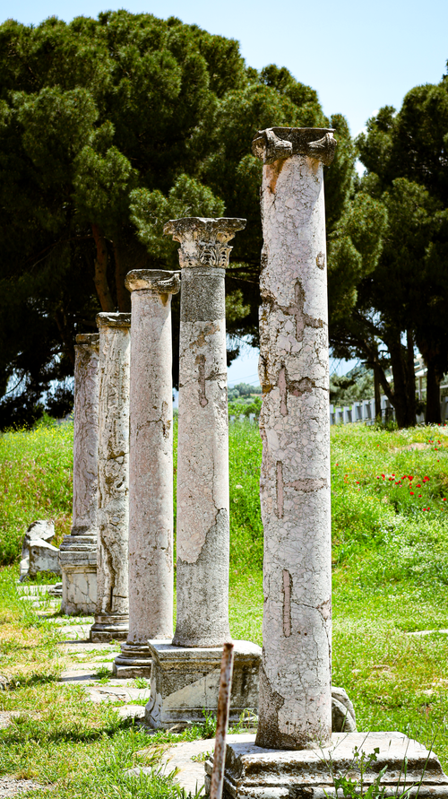 Free A row of ancient Roman stone columns in a sunny outdoor setting. Stock Photo