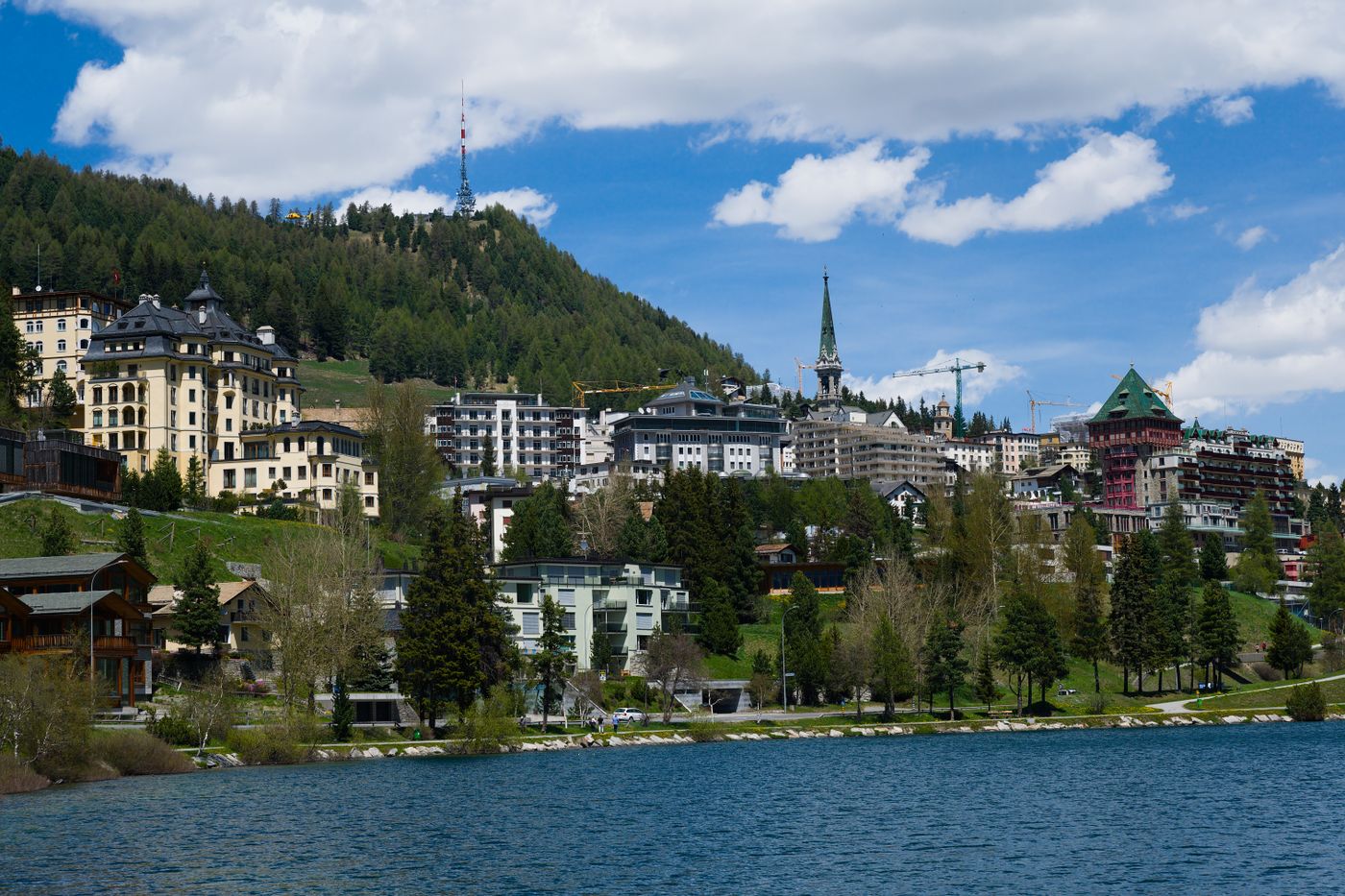 Daytime view of St Moritz, Switzerland, with its classic architecture beside the lake, mountains behind. Summer/warm-season photo, not snow.
