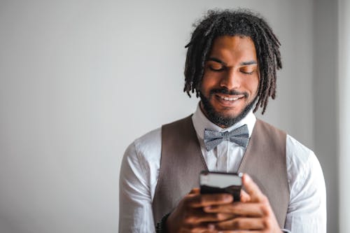 免费 白色礼服衬衫和棕色waistcoat Texting的男人微笑着的肖像照片 素材图片