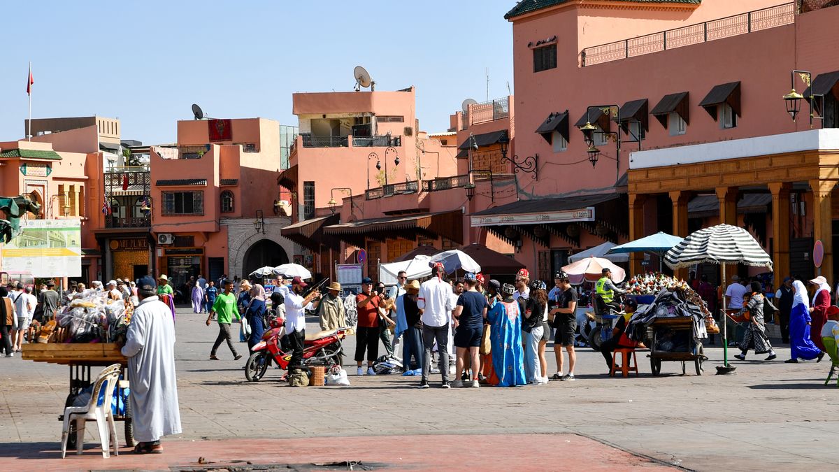 마라케시 — Lively market scene in Marrakesh with people shopping in Jemaa el-Fnaa square on a sunny day.