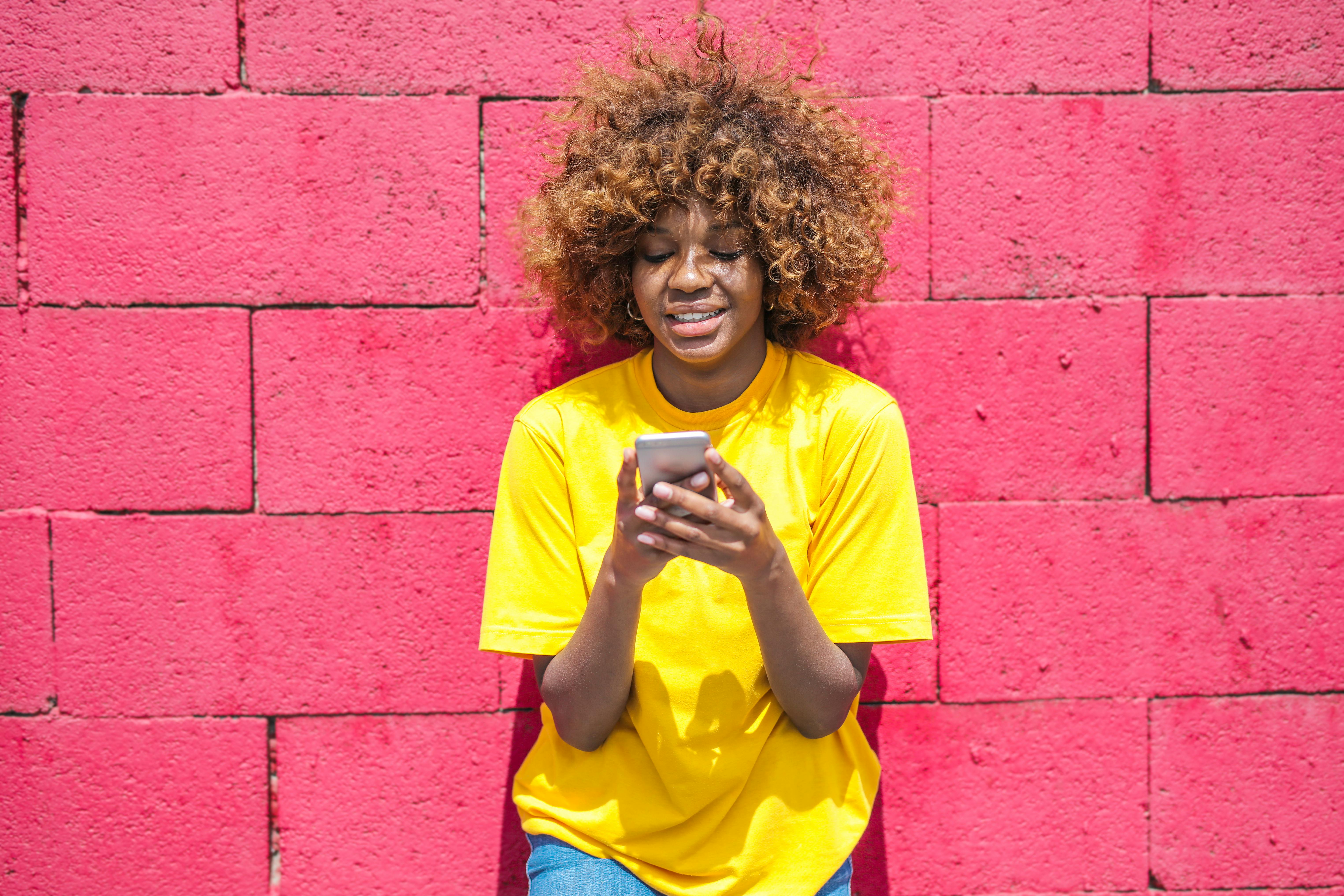 woman in yellow shirt holding cellular phone