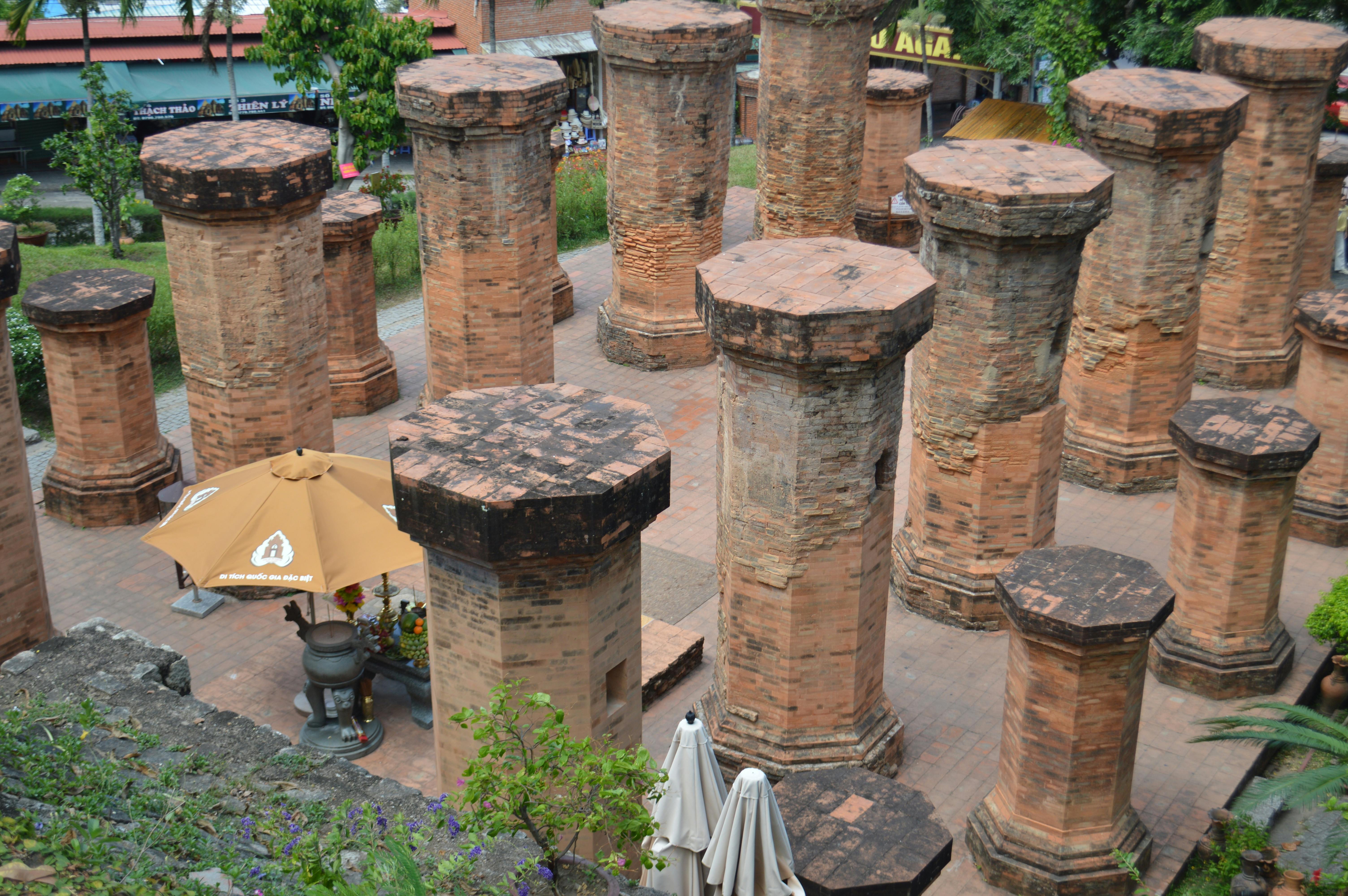 Ancient brick towers in a historical site with lush greenery, viewed from above.