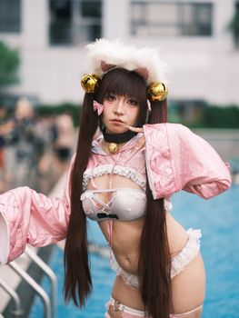 Cosplayer in an anime-inspired pink outfit poses playfully by a pool, exuding charm and creativity.