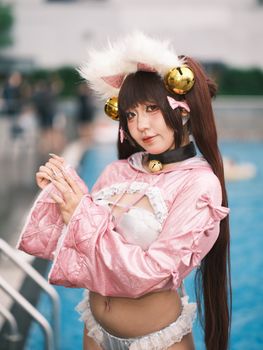 Cosplayer in pink costume poses by the pool, showcasing detailed outfit.