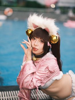 Anime-inspired cosplay pose near a pool with pink costume and accessories.