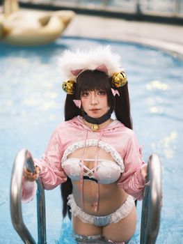 A cosplayer in a playful pink outfit poses by the pool, blending fantasy and fun.